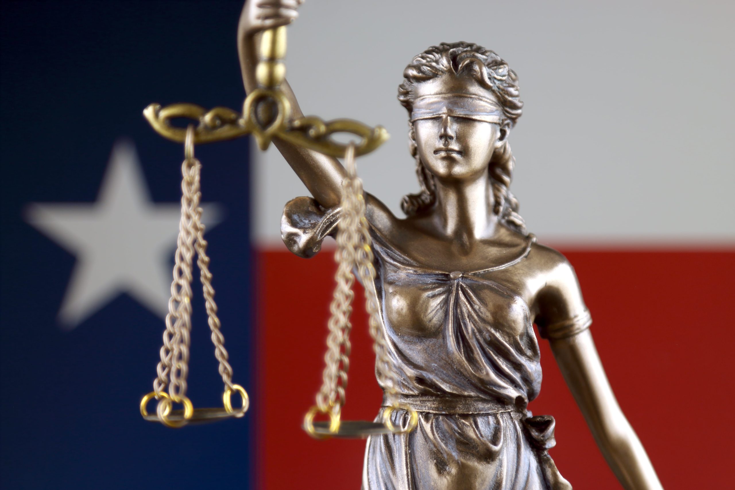 Lady Justice in front of a Texas flag